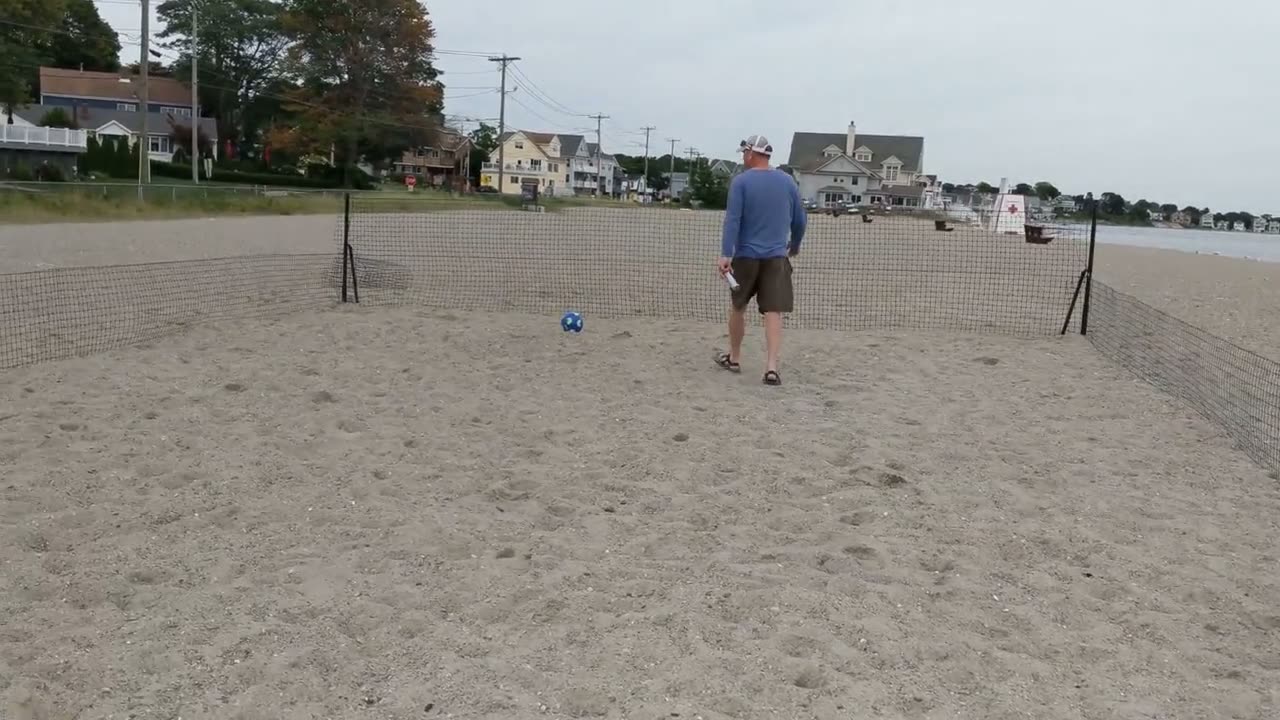The field on the sand: Posts and netting driven straight into the sand, then a game beside the water.