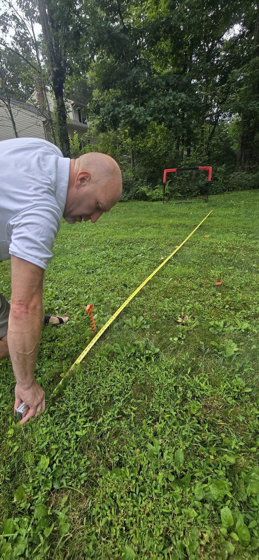 A man kneeling on the grass placing a marker along the yellow tape line
