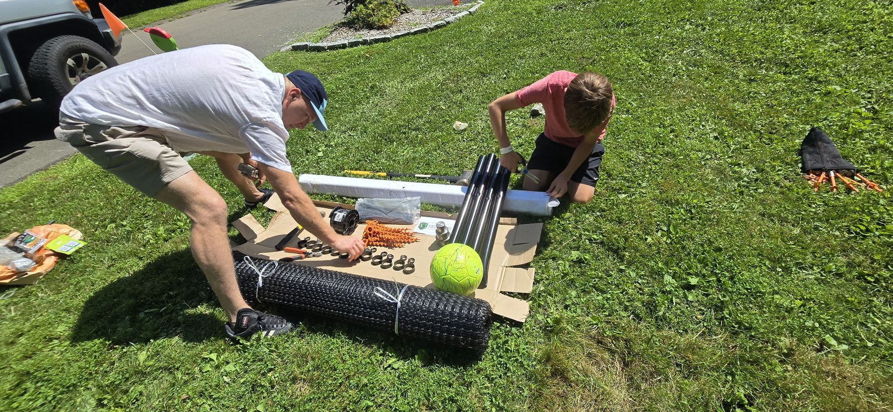 Two people moving the rolled SoccerYards wall panel into position on the grass