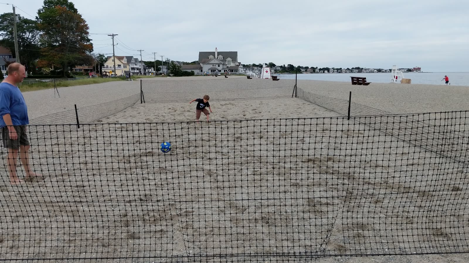 Low view along the beach perimeter netting with a ball at the far side