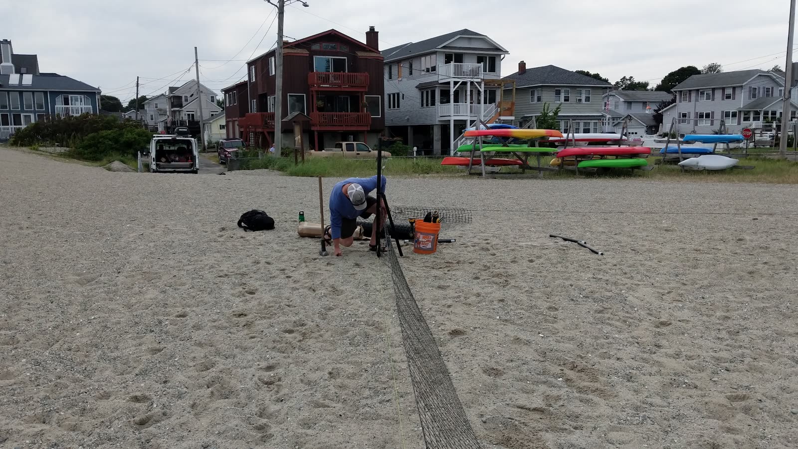 Beach setup in progress with tools and a hardware bucket beside the part-built perimeter